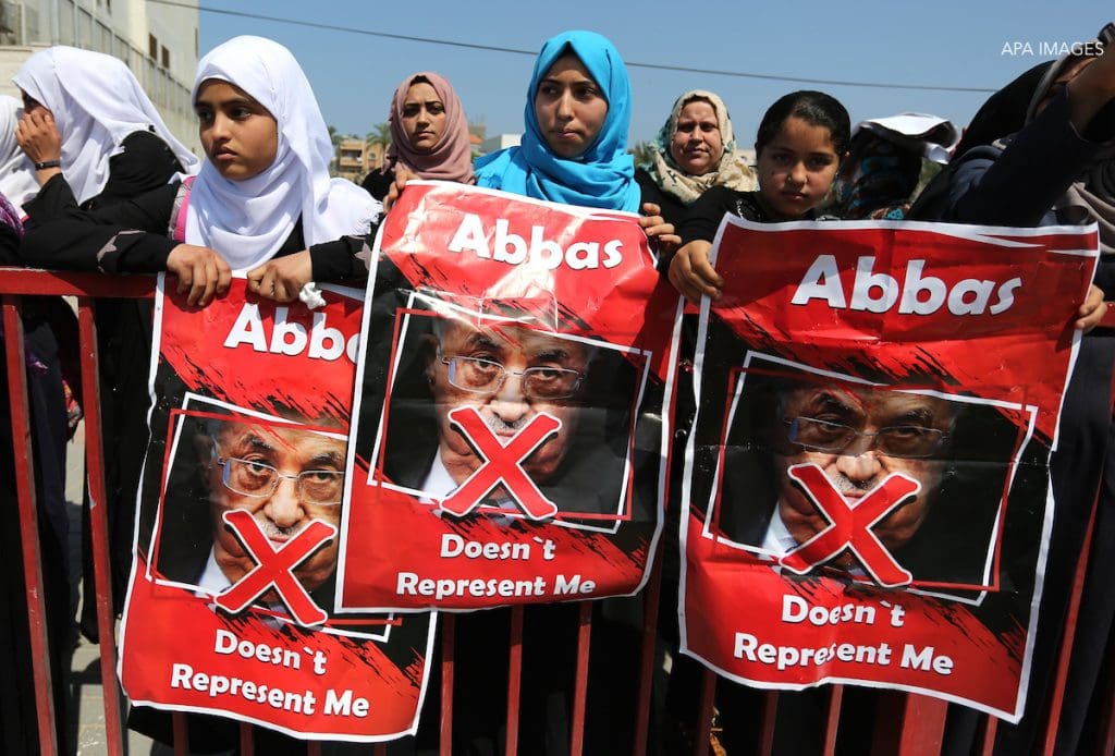 Palestinians hold a poster depicting Palestinian President Mahmoud Abbas during a protest against the blockade